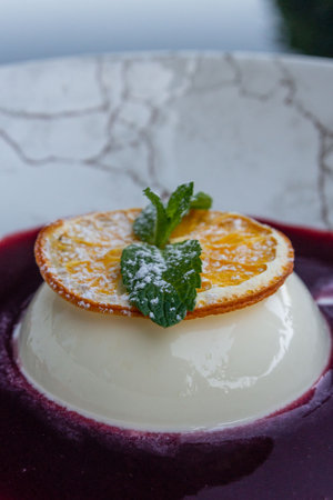 A slice of orange and mint leaves on the famous Italian dessert Panna cotta.の写真素材