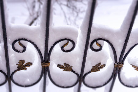 Elements of a wrought iron fence covered with snow. Snowy winter background.の写真素材