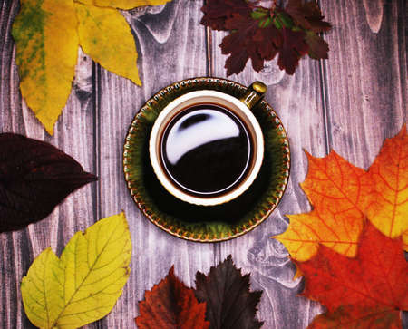 RUSSIA - SEPTEMBER 2020: Pictured is a cup of espresso coffee surrounded by autumn leaves. Background - boards.の写真素材