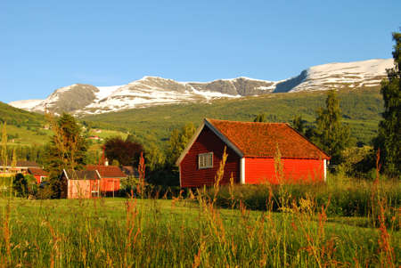 Pictured is a typical Norwegian landscape with mountains and a waterfall. Summer, sunny.
