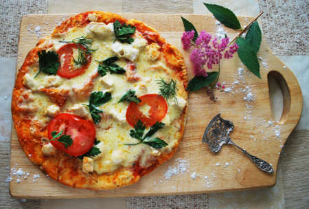 Russia - July 2020: Another still life with pizza, spatula and flower. The pizza is on the board.の写真素材