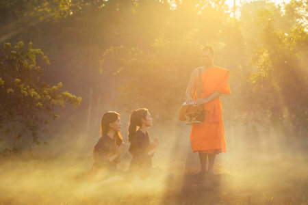 SAKONNAKHON, THAILAND â FEBRUARY 5: Two young Asian women were sitting in the bowl feeding the monks standing in front on February 5, 2017 in Sakonnakhon, Thailand.のeditorial素材