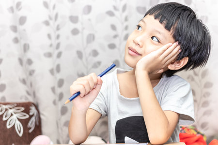 Little boy thinking about somthing and looking up, confused about an idea. Small child hand holding pencil.の写真素材