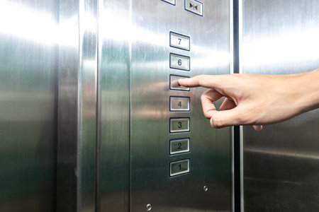 The hand presses on the fifth floor button in the elevator. Man finger pressing the elevator button.の写真素材