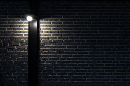 Wall light on black brick wall. Dark brick wall with lamp above.の写真素材
