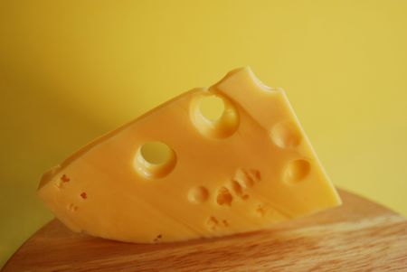 Piece of cheese on a yellow backgroundの写真素材
