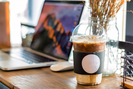 A plastic cup of cold coffee placed on wood table andの写真素材