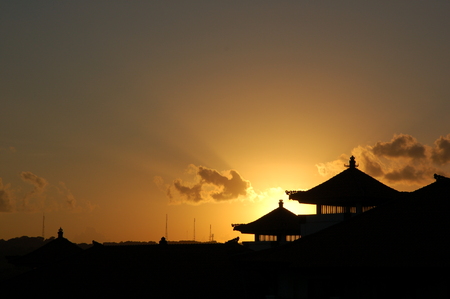 A gorgeous sunset and beautiful view of silhouettes of a house with a traditional balinese roofs, Bali island, Indonesia, for travel themeの写真素材