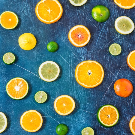 Citrus pattern on blue wooden background. Assorted citrus fruits. Slices of orange, tangerine,...