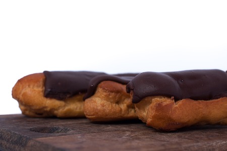 Sweet delicious three chocolate eclairs isolated on white. Traditional french cakes cooked from choux dough filled with a creamの写真素材