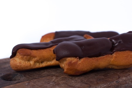 Sweet delicious three chocolate eclairs isolated on white. Traditional french cakes cooked from choux dough filled with a creamの写真素材