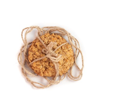 delicious homemade nut oat cookies tied up with brown rope, on isolated white backgroundの写真素材