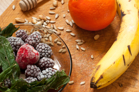 banana, orange,frozen strawberries blackberries and seeds vivid smoothie ingredients on the wooden backgroundの写真素材