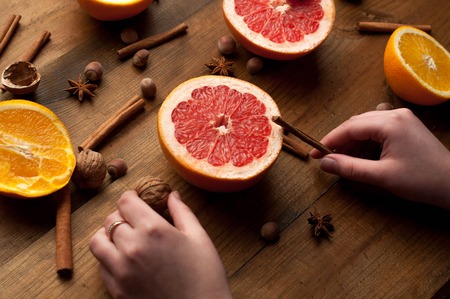 slices of oranges, lemons and grapefruits on vintage wood table. Citrus fruit with star anise, cinnamon. healthy eating with natural vitamins. holding hands in.の写真素材
