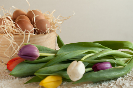 Easter holiday basket with eggs, flowers and easter bunny on rustic wooden Easter rabbit with eggs tulipsの写真素材