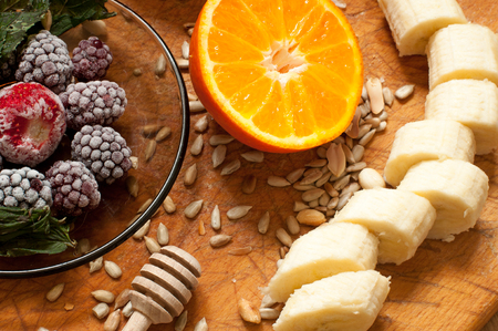 banana, orange,frozen strawberries blackberries and seeds vivid smoothie ingredients on the wooden backgroundの写真素材