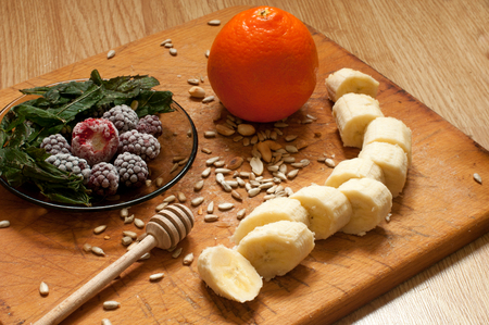 banana, orange,frozen strawberries blackberries and seeds vivid smoothie ingredients on the wooden backgroundの写真素材