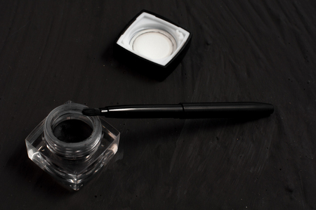 Eyeliner and brush on black background. Makeup set background.の写真素材