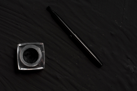 Eyeliner and brush on black background. Makeup set background.の写真素材