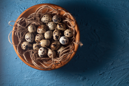 quail eggs in wooden bowl isolated on blue background. close upの写真素材
