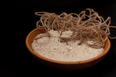 Closeup rice in wooden bowl with wooden spoon on black backgroundの写真素材