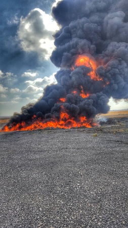 red beautiful fire on the asphalt with black and orange smoke rising to the skyの写真素材