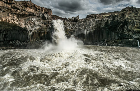 The bubbling, muddy waters of the Aldeyarfoss waterfall under a threatening sky, Icelandの写真素材