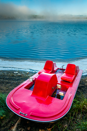 A pedal boat on the edge of a lake early in the morning in Saint-aime-des-Lacs in Quebec, province of Canadaの写真素材