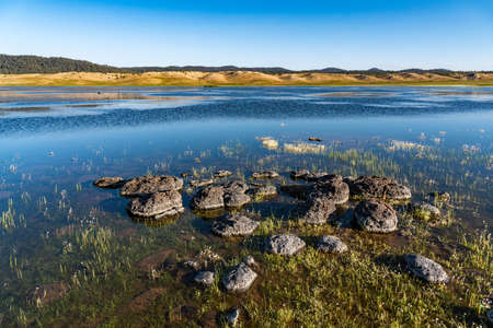 Lake Afnourir in Morocco. Grass and flowers grow in the water of the lake among the rocks that line...