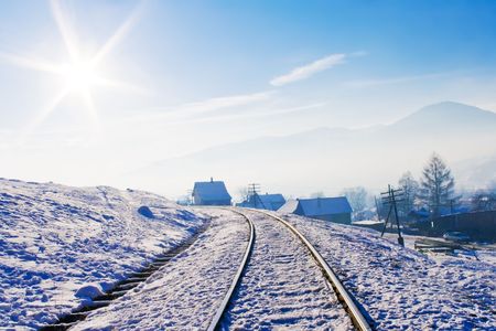 Railroad in snow covered mountains under blue sunny sky in wintertimeの写真素材