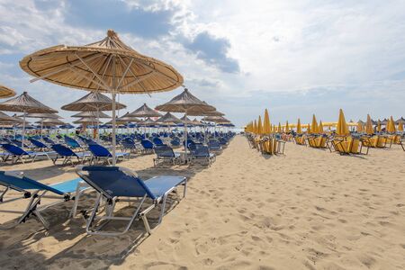 DURRES, ALBANIA - JUNE 2019 Sandy Beach with Blue and Yellow Deck Chairs and Reed Shades earley in the morning 1070のeditorial素材