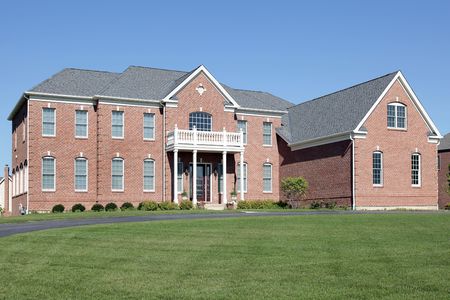 Large brick home with balcony and front columnsの写真素材