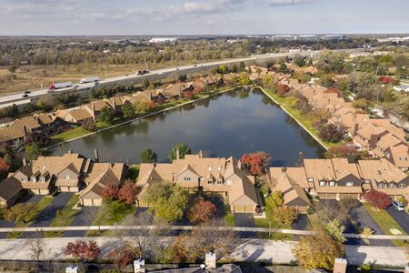 Aerial view of a townhouse community with pond beside an expressway in a suburban setting.の写真素材