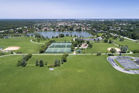 Aerial view of a large playfield in a suburban area with ballfields, tennis courts, and a lake.の写真素材