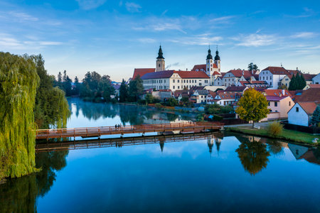 Aerial view before sunrise with three photographers on a bridge in front of the Telc Castle with foreground pond and castle reflections in the Czech Republic.のeditorial素材