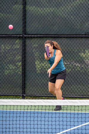 A pickleball player serves the ball on a suburban pickleball court during summer.の写真素材