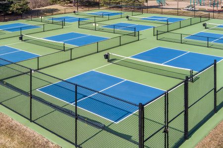 Aerial view of a pickleball complex with blue and green courts beside a playground in a suburban park in early spring.の写真素材