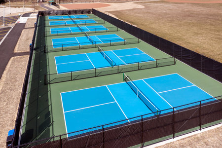 Aerial view of a new pickleball facility with blue and green courts in a suburban park in early spring.の写真素材