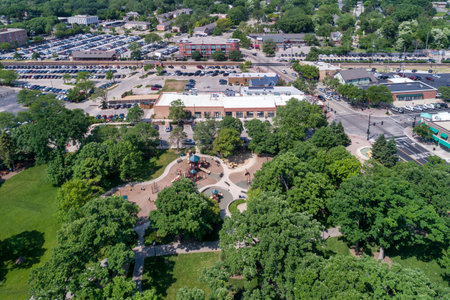 Aerial view of a playground and park adjacent to a business district with stores and a commuter train in Northbrook, IL.の写真素材