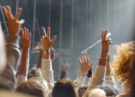 A group of people with their hands raised at a concertの写真素材
