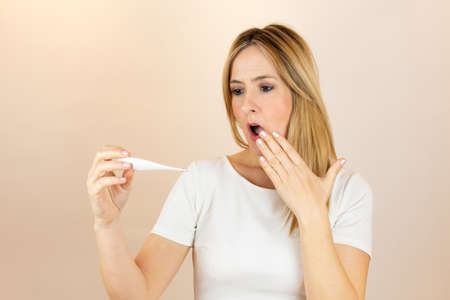 Woman looking at thermometer and is in shockの写真素材