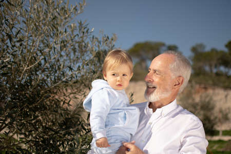 Grandfather with his grandson in his arms in nature