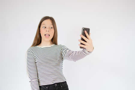 Girl with striped shirt taking a picture with her phoneの写真素材