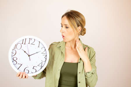 Beautiful woman looking at the clock with surprise