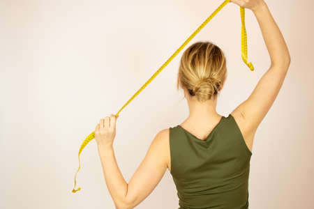 Blond woman on back with tape measure in handsの写真素材