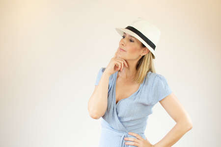 Beautiful woman wearing blue dress and hat making thoughtful gesture
