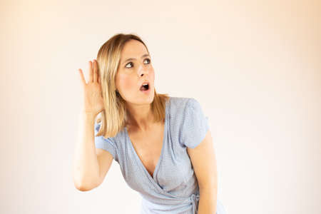 Young pretty woman wearing blue dress and making listening gestureの写真素材