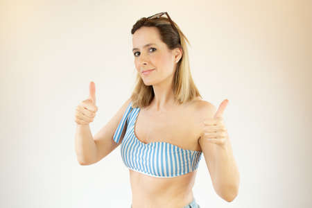 Beautiful woman wearing bikini is making fingers up gestureの写真素材