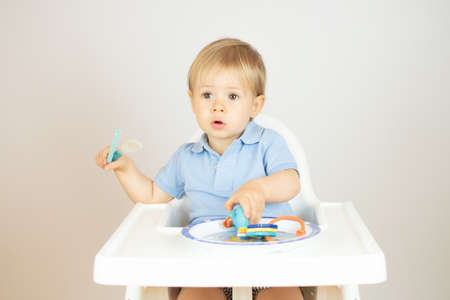 Blond baby with blue polo shirt sitting and gesturingの写真素材