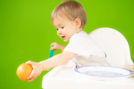 Blond baby sitting in the high chair and smilingの写真素材